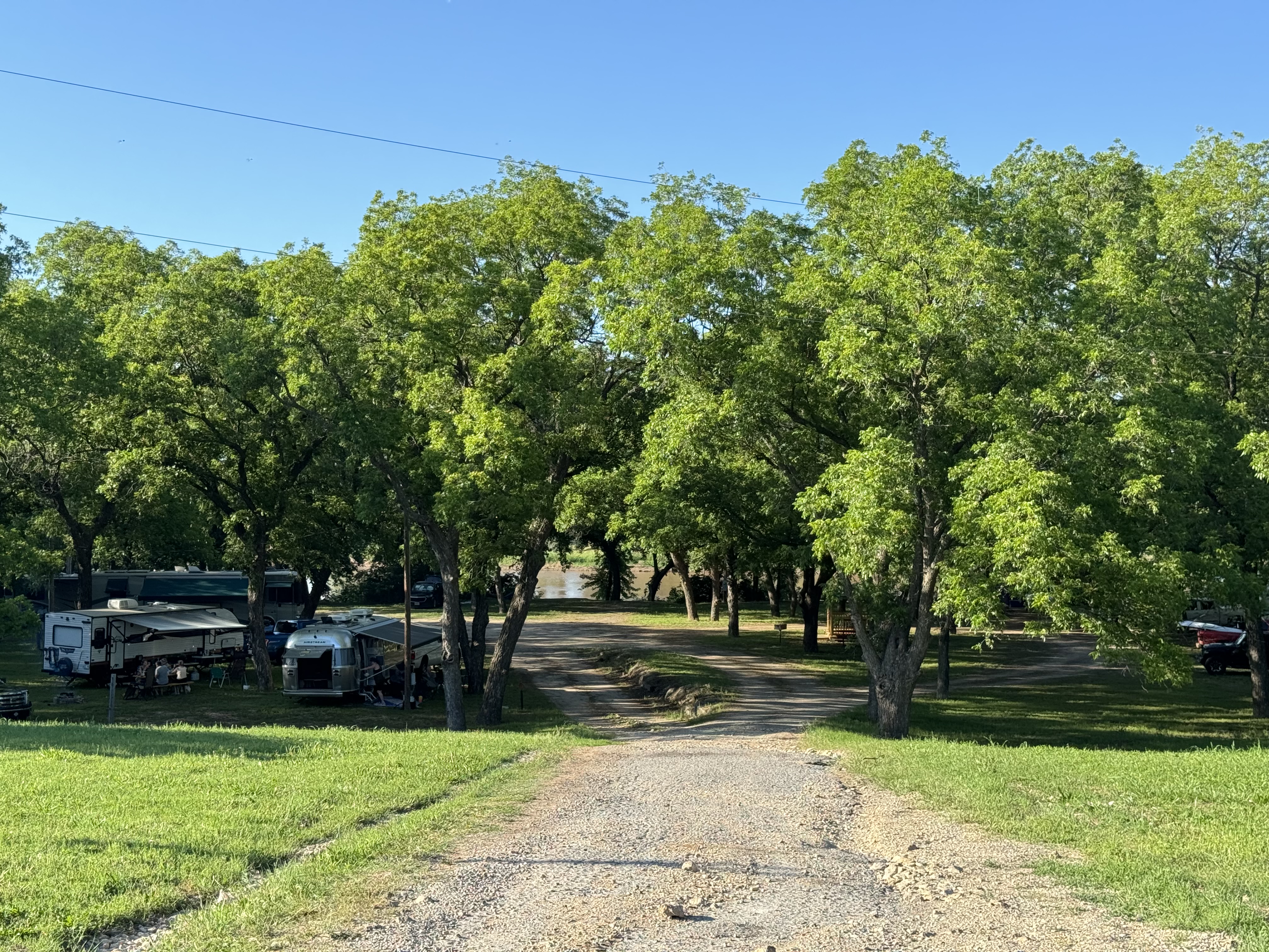 Tree-lined entrance to Rivershire RV Resort in summer